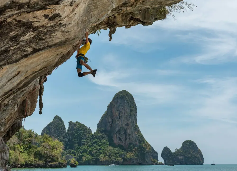 Climber ascending a steep rock face above the sea