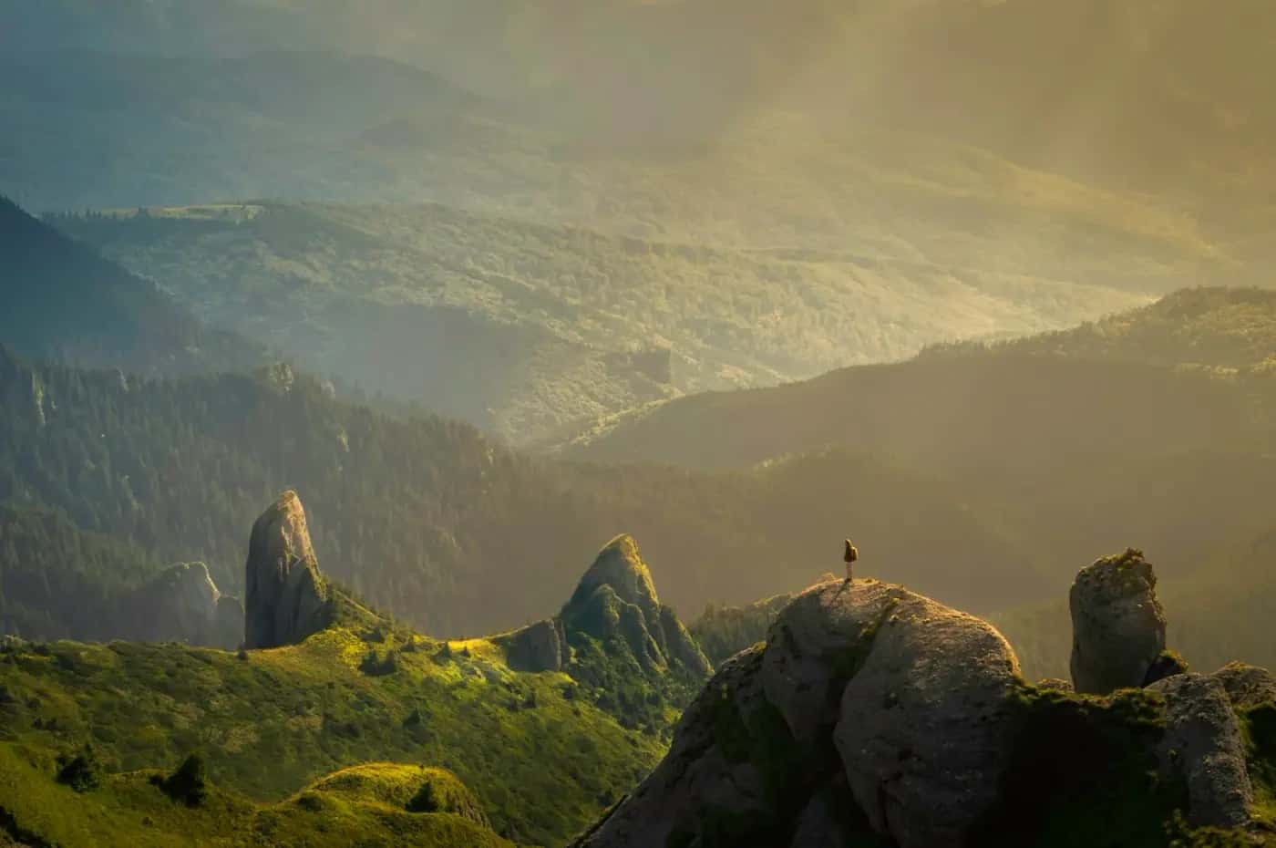 Traveller on a rocky ridge above sunlit mountains